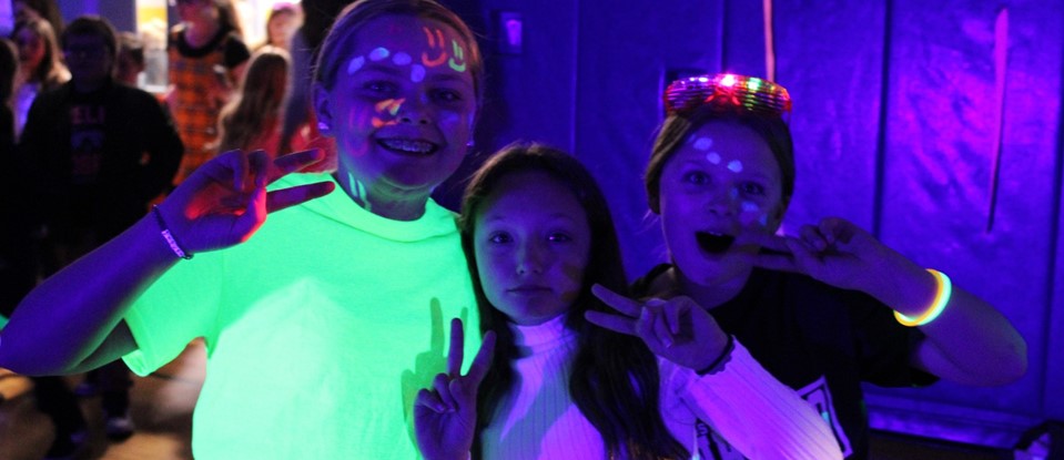 students wearing glow sticks and paint at school event