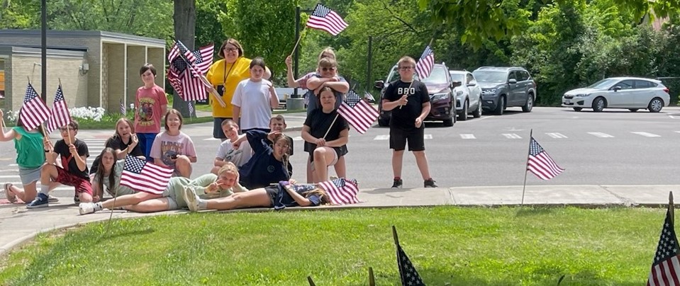 students posing for photo with flags to decorate the sidewalk
