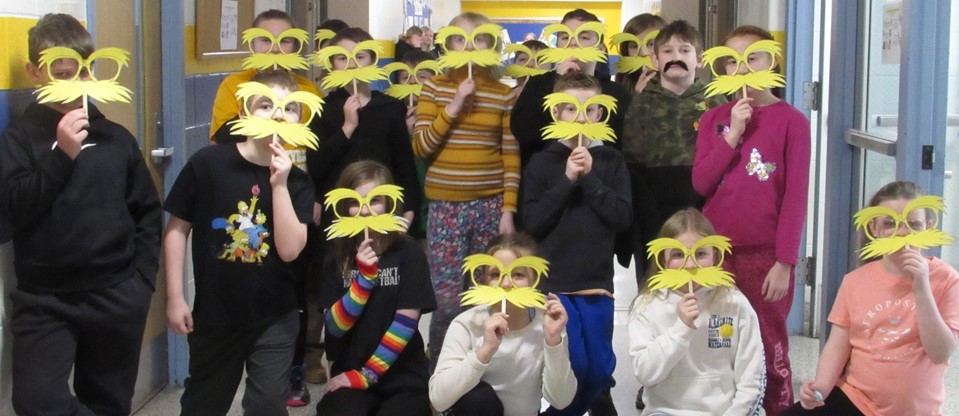 elementary students holding up Lorax masks